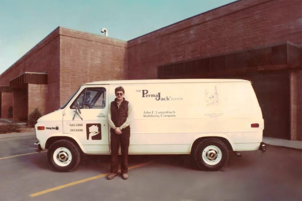 A man standing beside a white van parked in a parking lot.