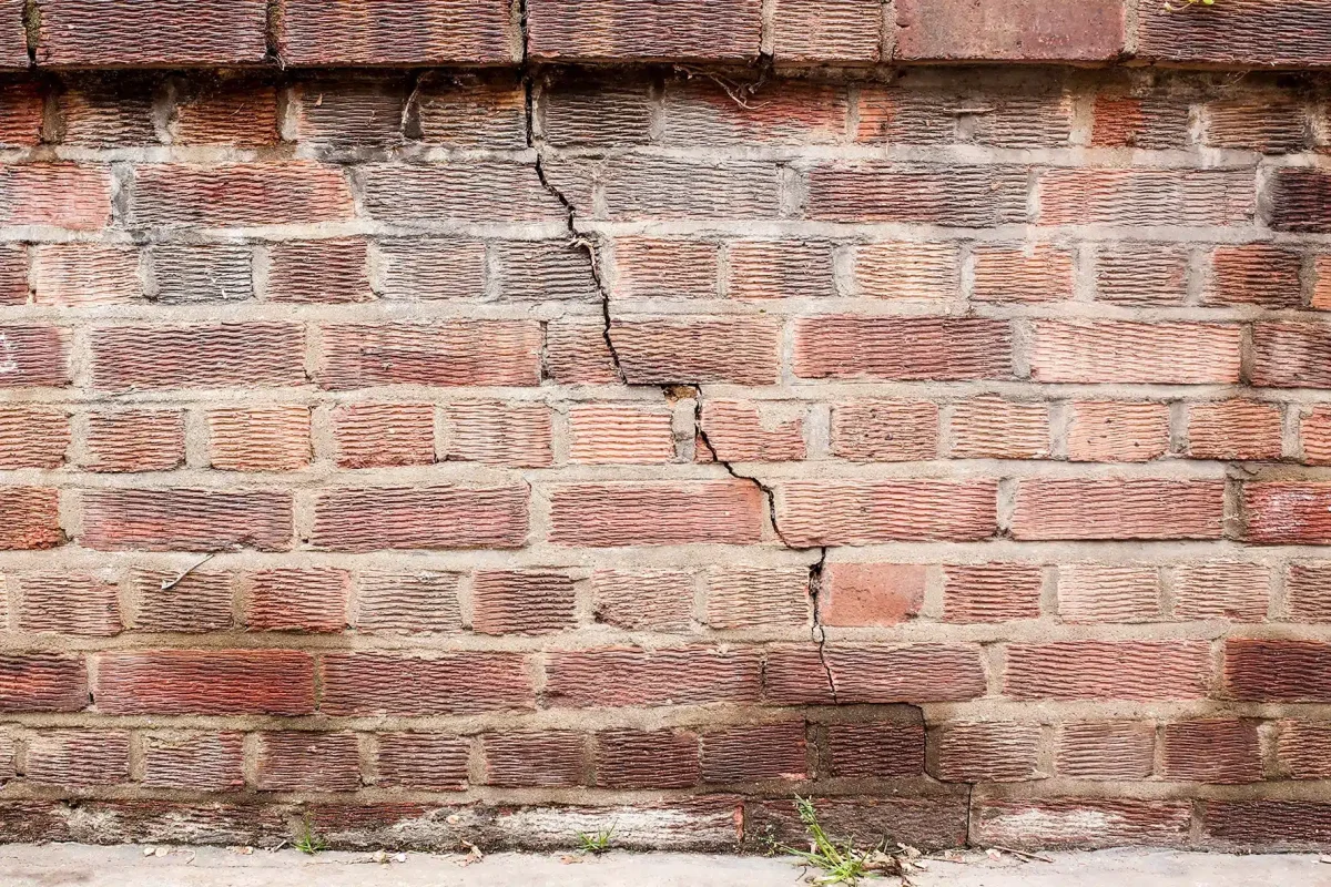 A weathered brick wall with visible cracks and fissures.