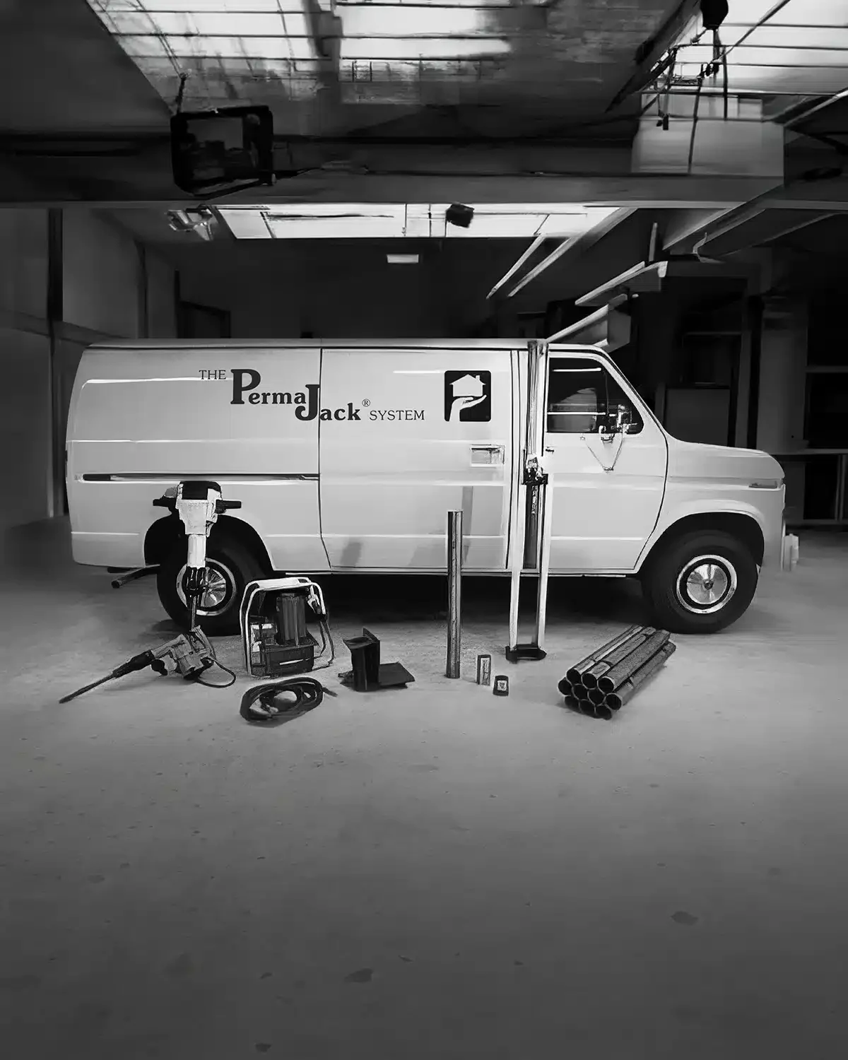 Van in a long garage surrounded by foundation repair equipment.